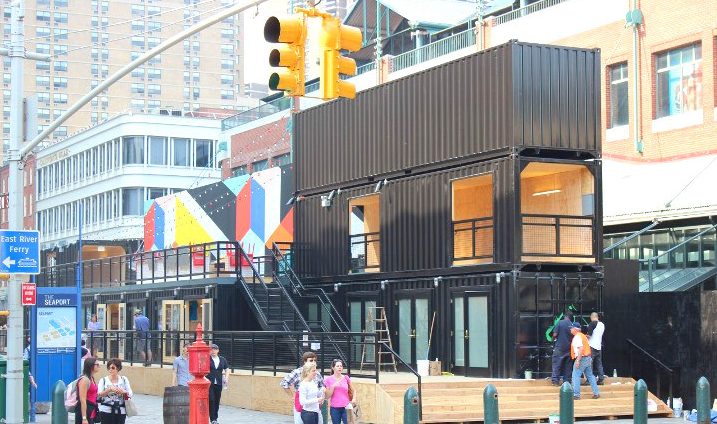 People walking on the street and enjoying restaurants made completely out of shipping containers